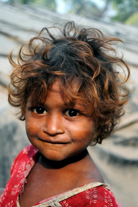 a little girl with curly hair smiling at the camera