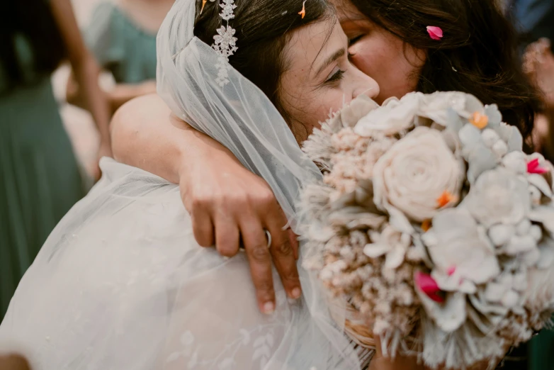 two women in wedding attire, one carrying a bouquet