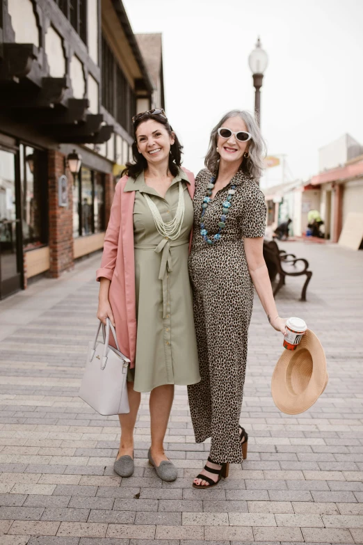 two women standing on the street in dresses and hats