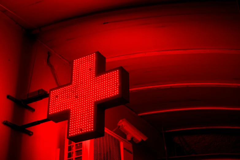 a red cross is lit in front of a window