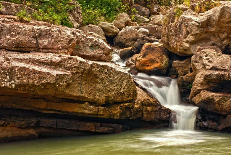 a waterfall cascades into a stream between two rocks