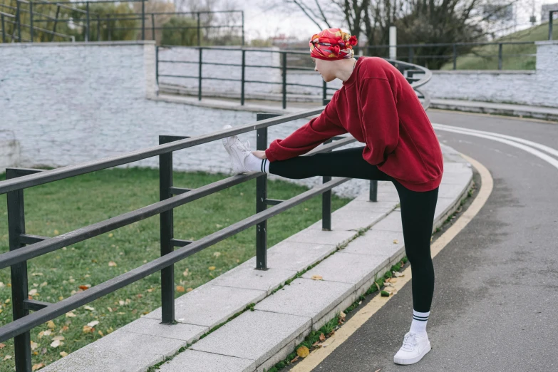 a woman stretches outdoors on the sidewalk