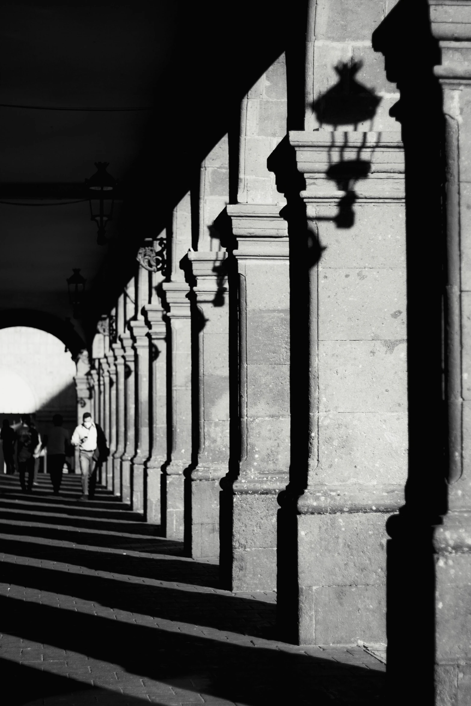 a couple of people walking under an arched streetlight