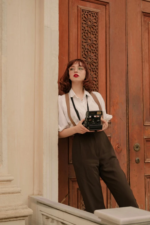 a woman is standing in front of a door with her camera