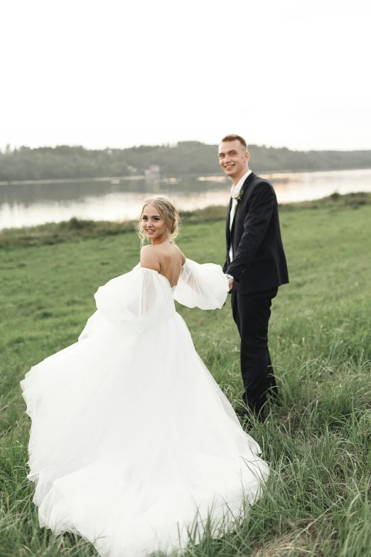 a couple stands holding hands near water