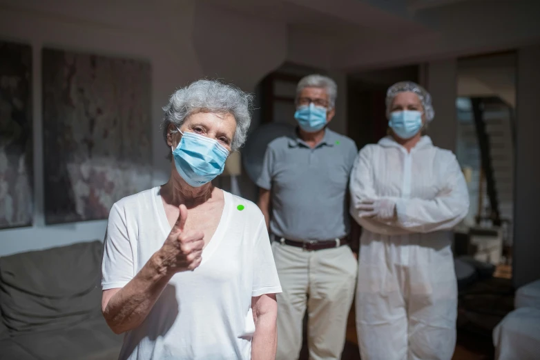 a woman wearing a face mask while three other people in white shirts and khaki pants stand behind her