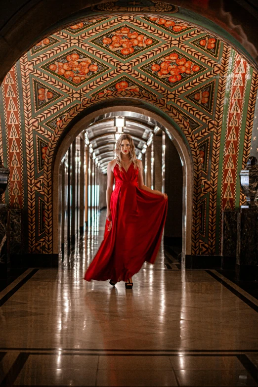 a woman dressed in red is standing in an arched hallway