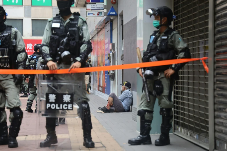 two men wearing helmets and holding on to an orange police line in front of a building with the same police outfit