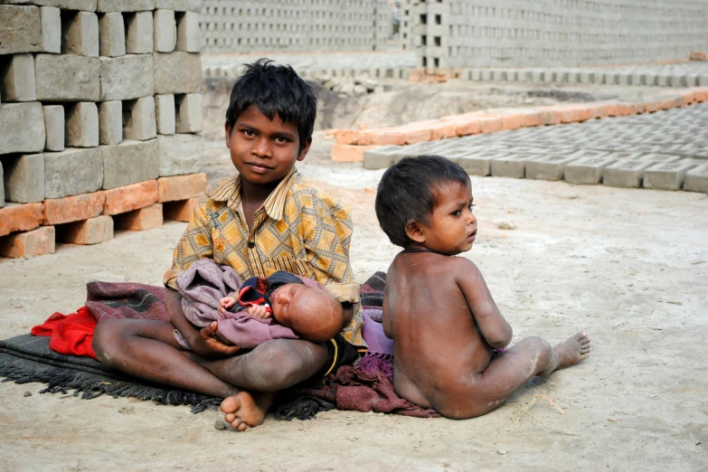 two boys sitting on the ground next to each other