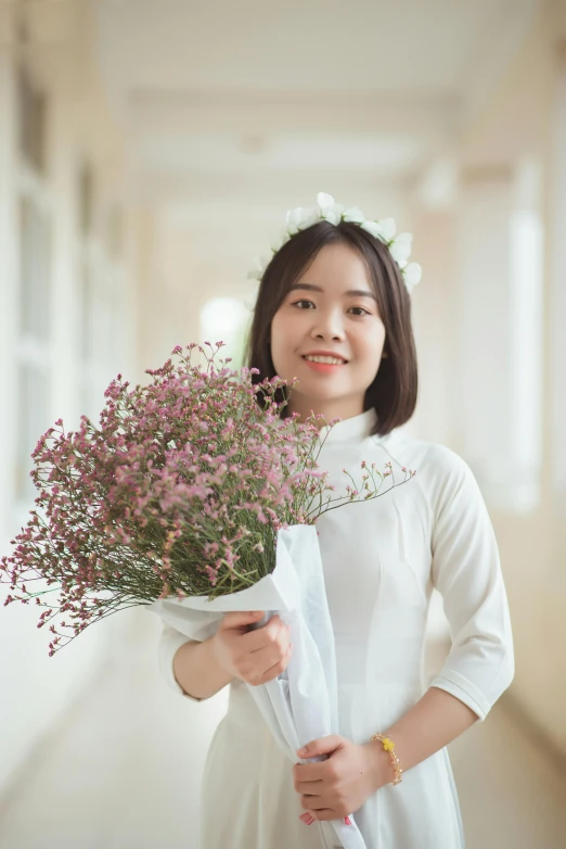 a woman wearing a white dress holds a bouquet of flowers