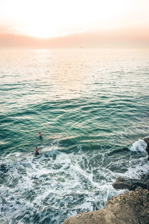 a couple of people standing on top of a sandy beach next to the ocean