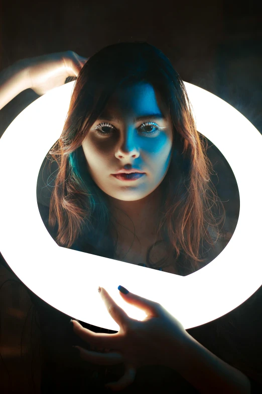 a woman holding a lit up ring in front of her face