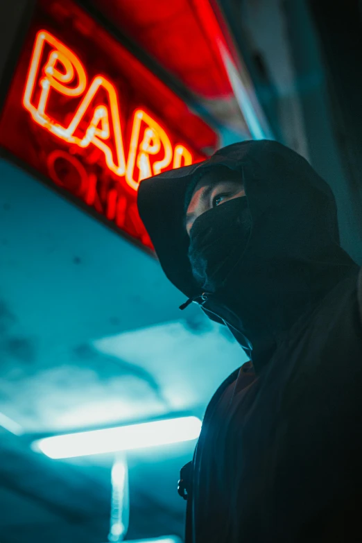 a man in a hood standing outside of a bar