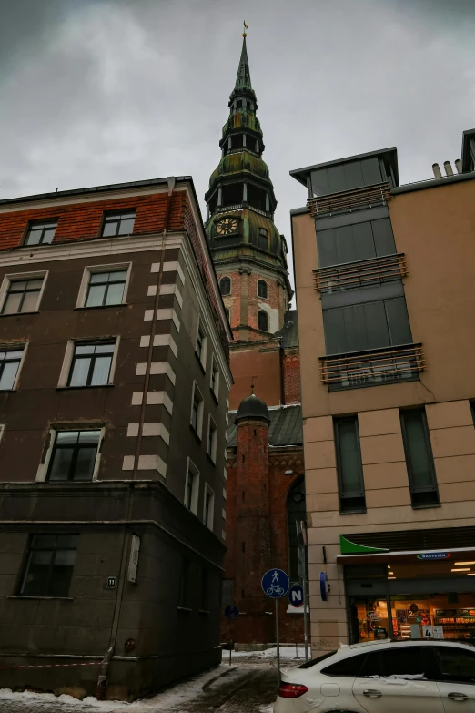 the tall clock tower of some buildings with lots of snow on it