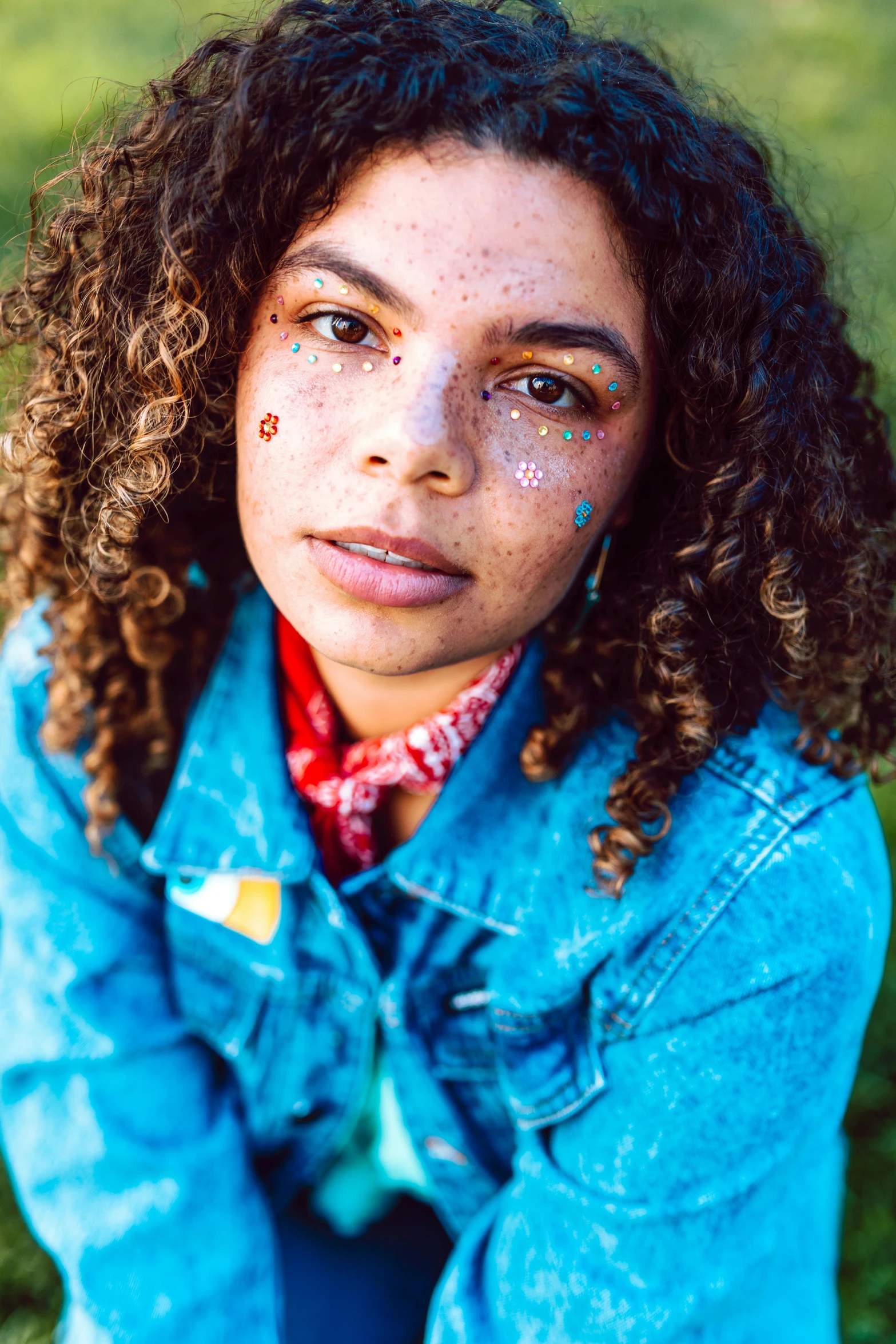 woman with freckles sitting outdoors on grass looking at camera