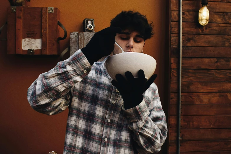 a man wearing gloves holding a bowl over his face