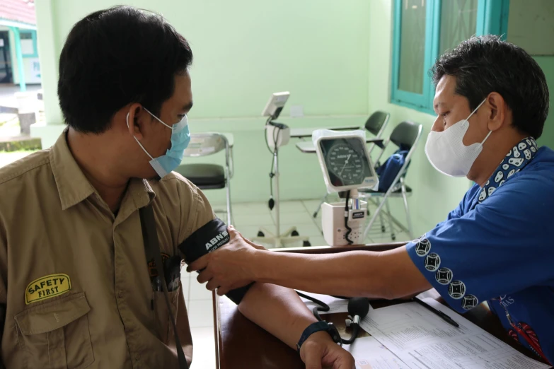 two men sitting in chairs wearing face masks