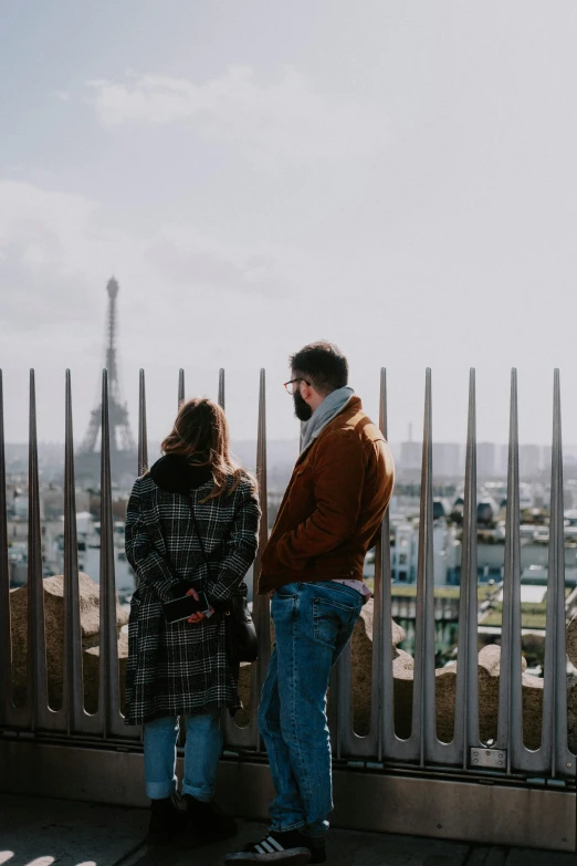 two people standing in front of a metal fence