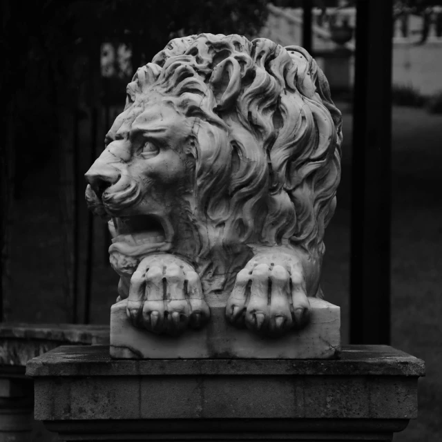 a lion sculpture sitting in front of a tall pole