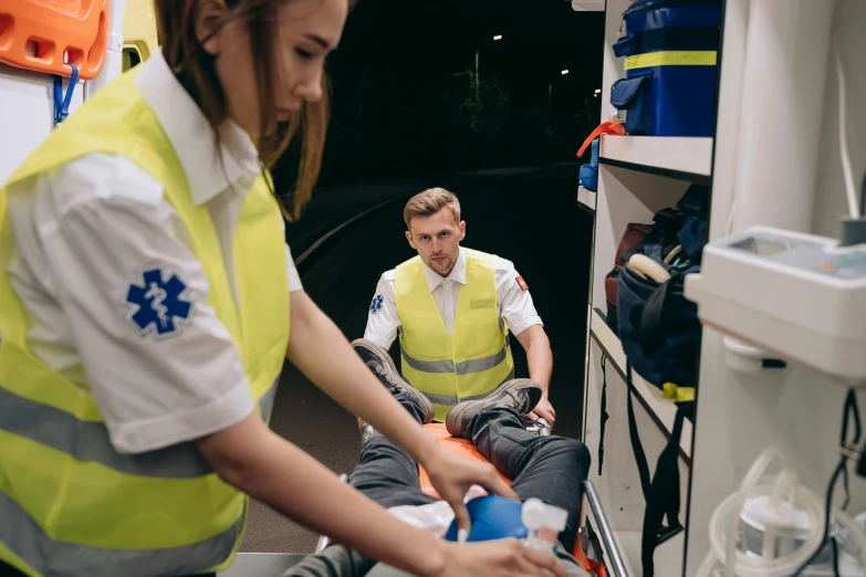 two people in yellow vests unloading items from an ambulance