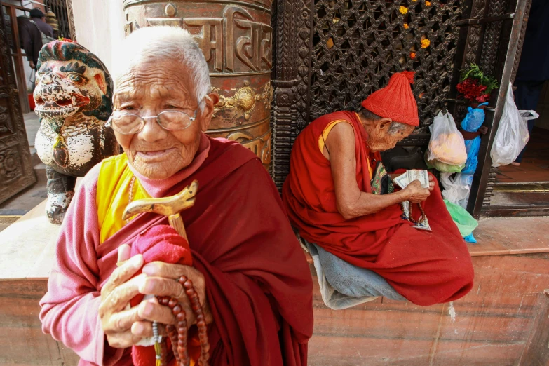 elderly woman and woman in red, yellow and red robes sitting together