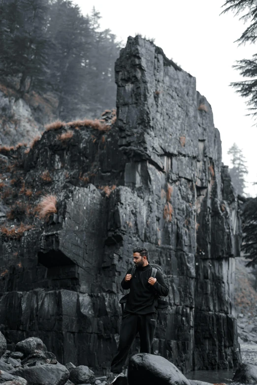 a man standing on rocks, near some trees