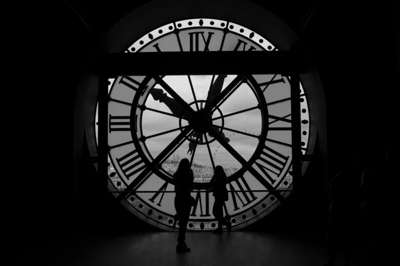 two people standing in front of a big clock