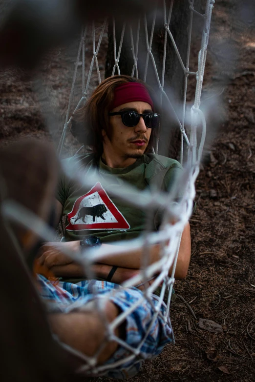 a young man wearing shades and sunglasses sits outside