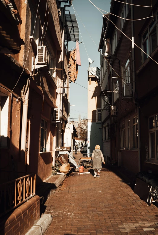 a girl walking on a cobblestone path next to a brick alley