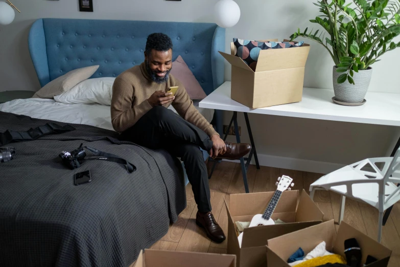 a man sits on the floor with a broken guitar in his room