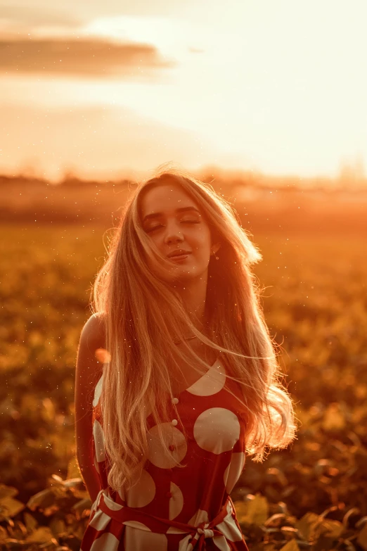 the young woman stands in a field and looks at the camera