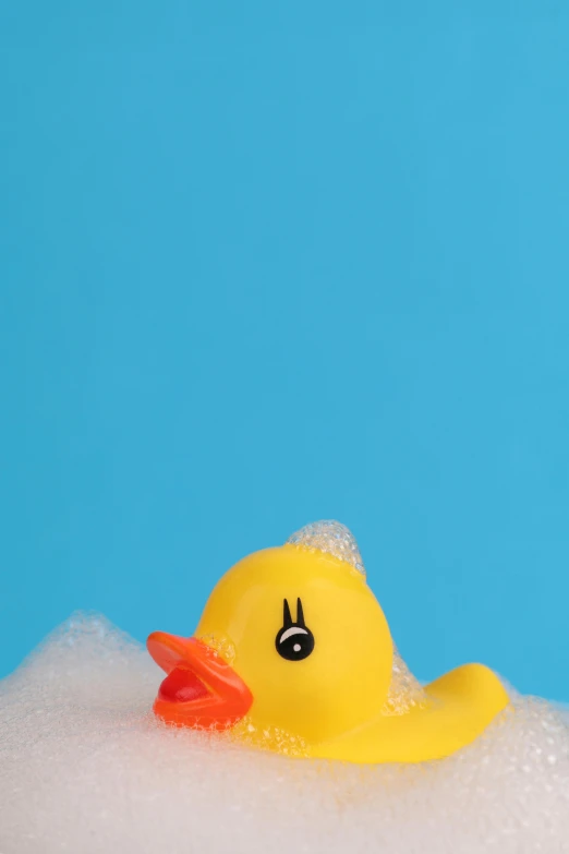 rubber ducky in foamy bathtub with mouth and bill on nose