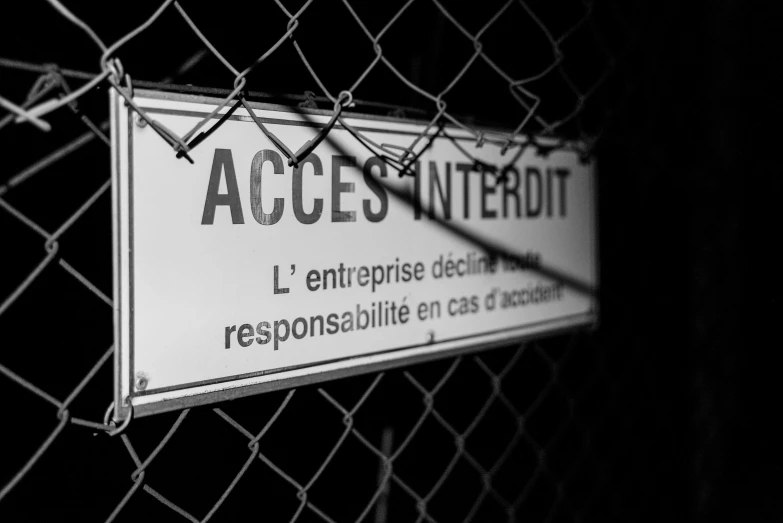 an image of a black and white sign attached to a chain link fence