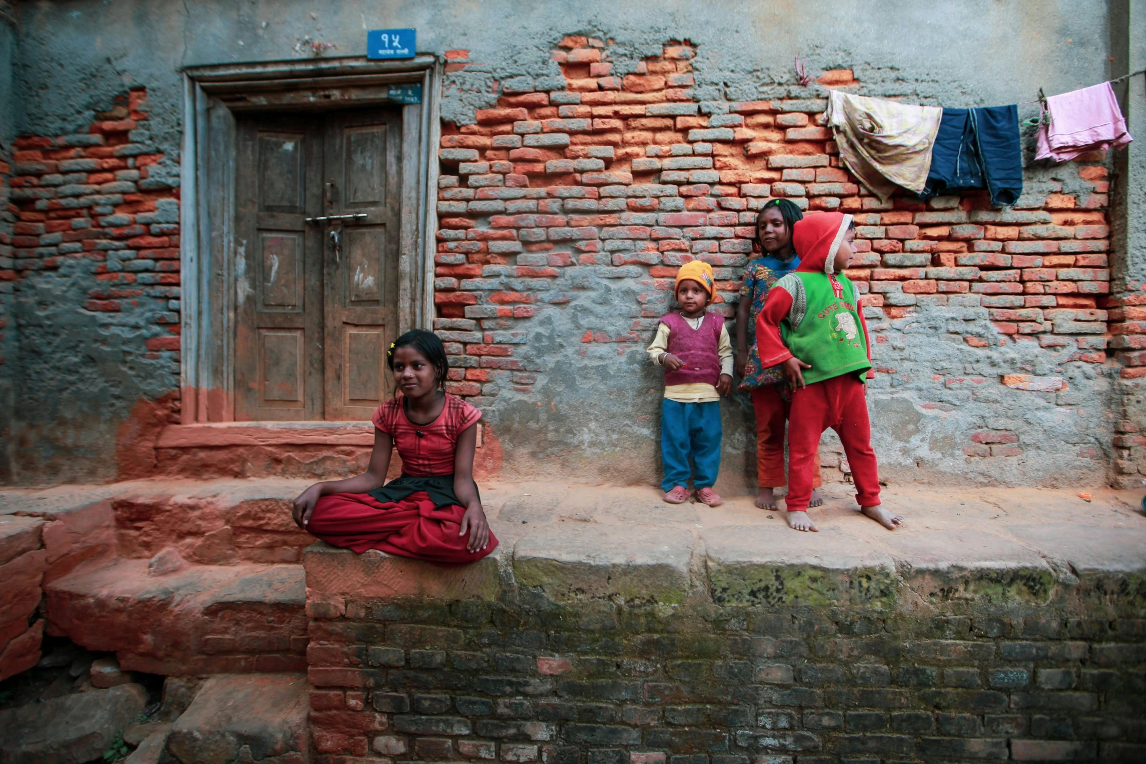 three s sitting on the sidewalk outside of their home