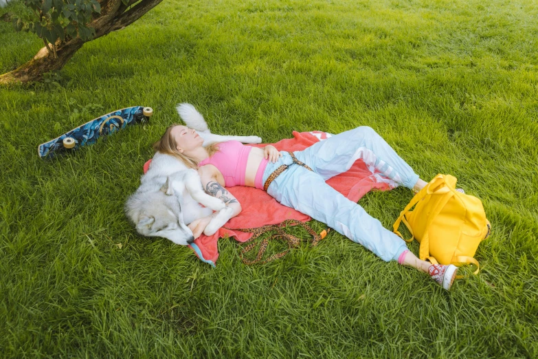 a woman is laying on the grass with her dog