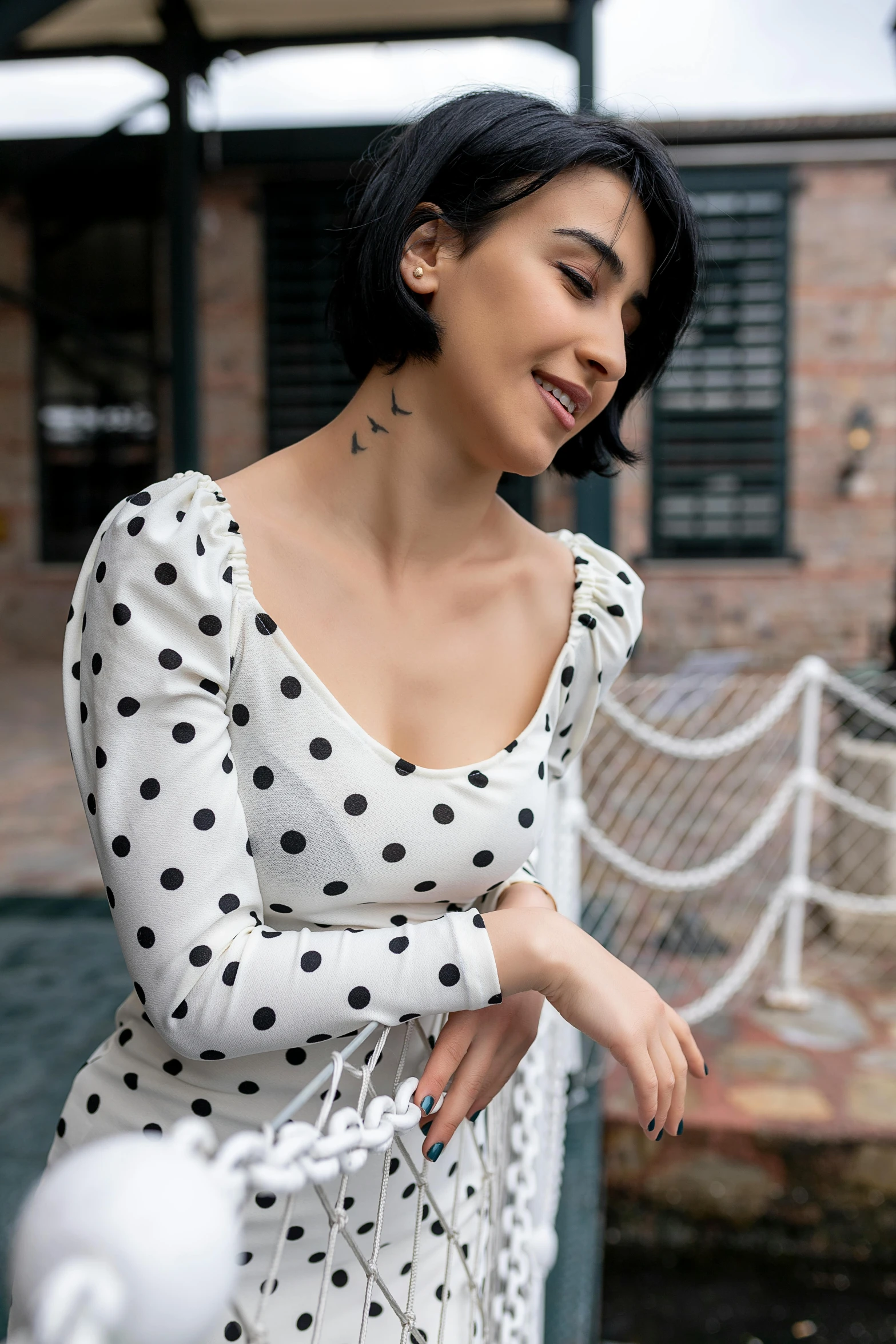 a woman in a dress smiles while wearing a polka dot necklace