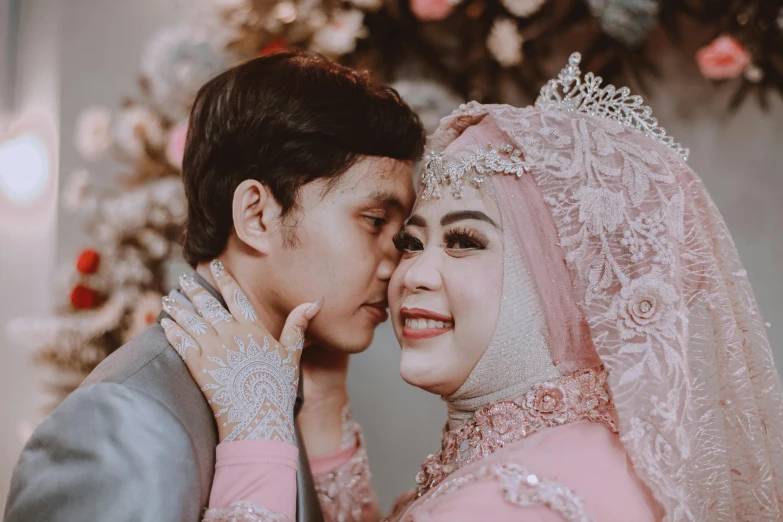 an asian man and woman kissing under a white veil