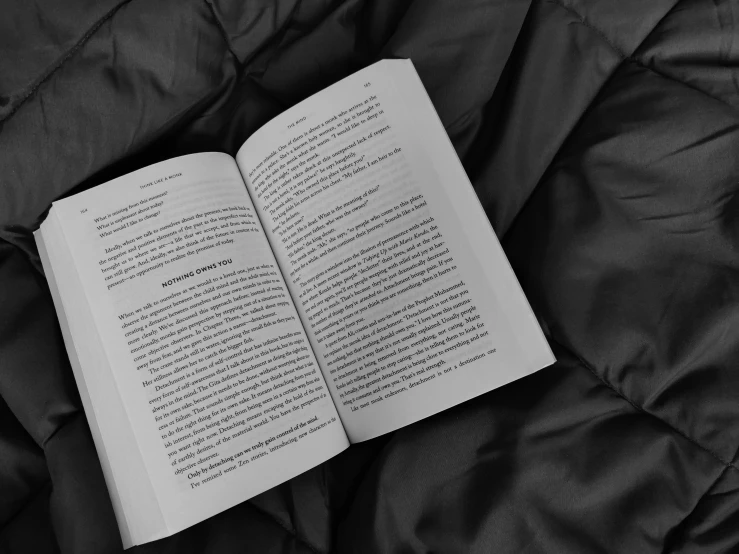 an open book laying on a bed that is black