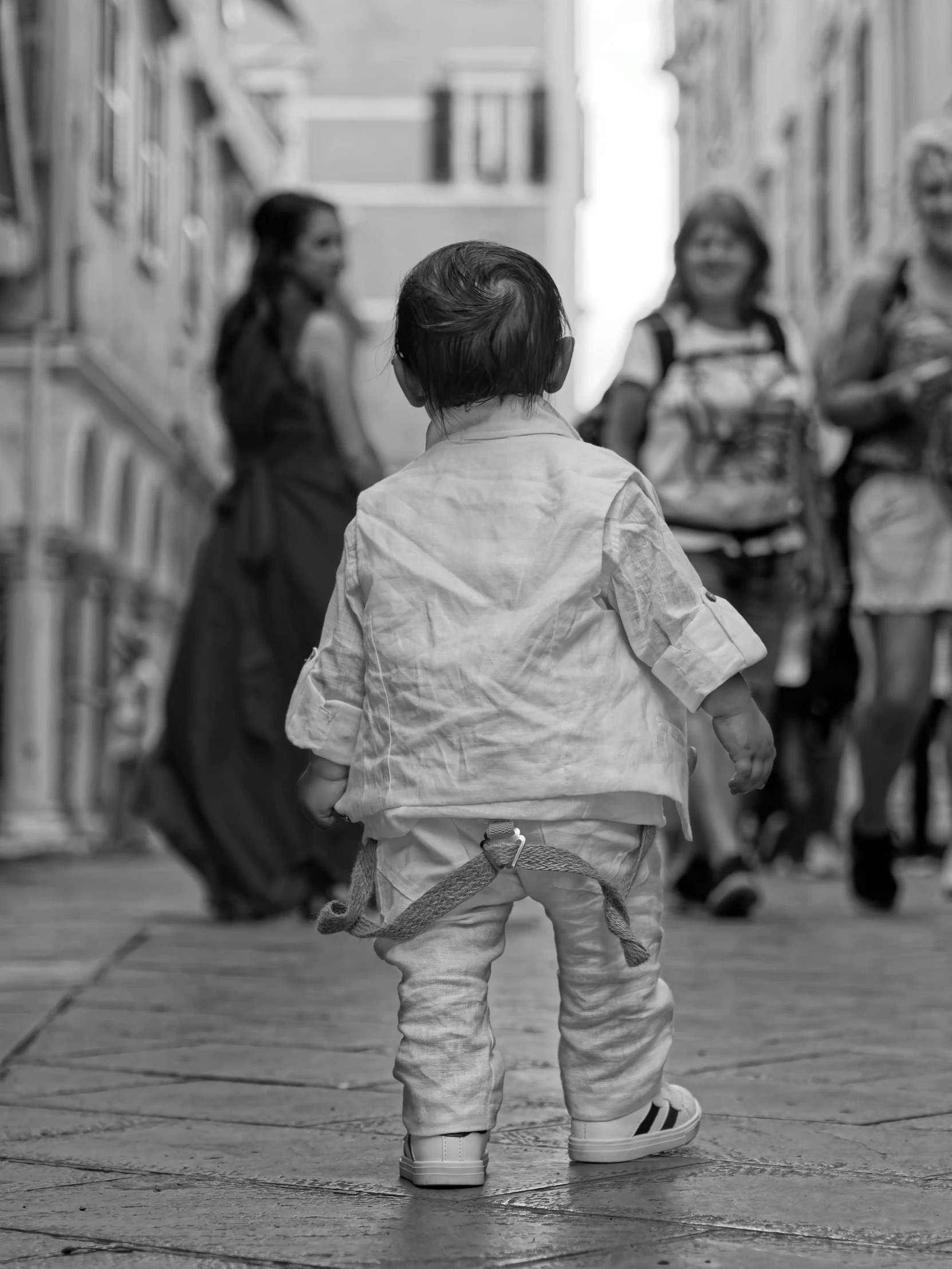 the child is walking down the narrow cobblestone street