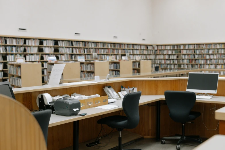 two desks with computers and chairs and book shelves