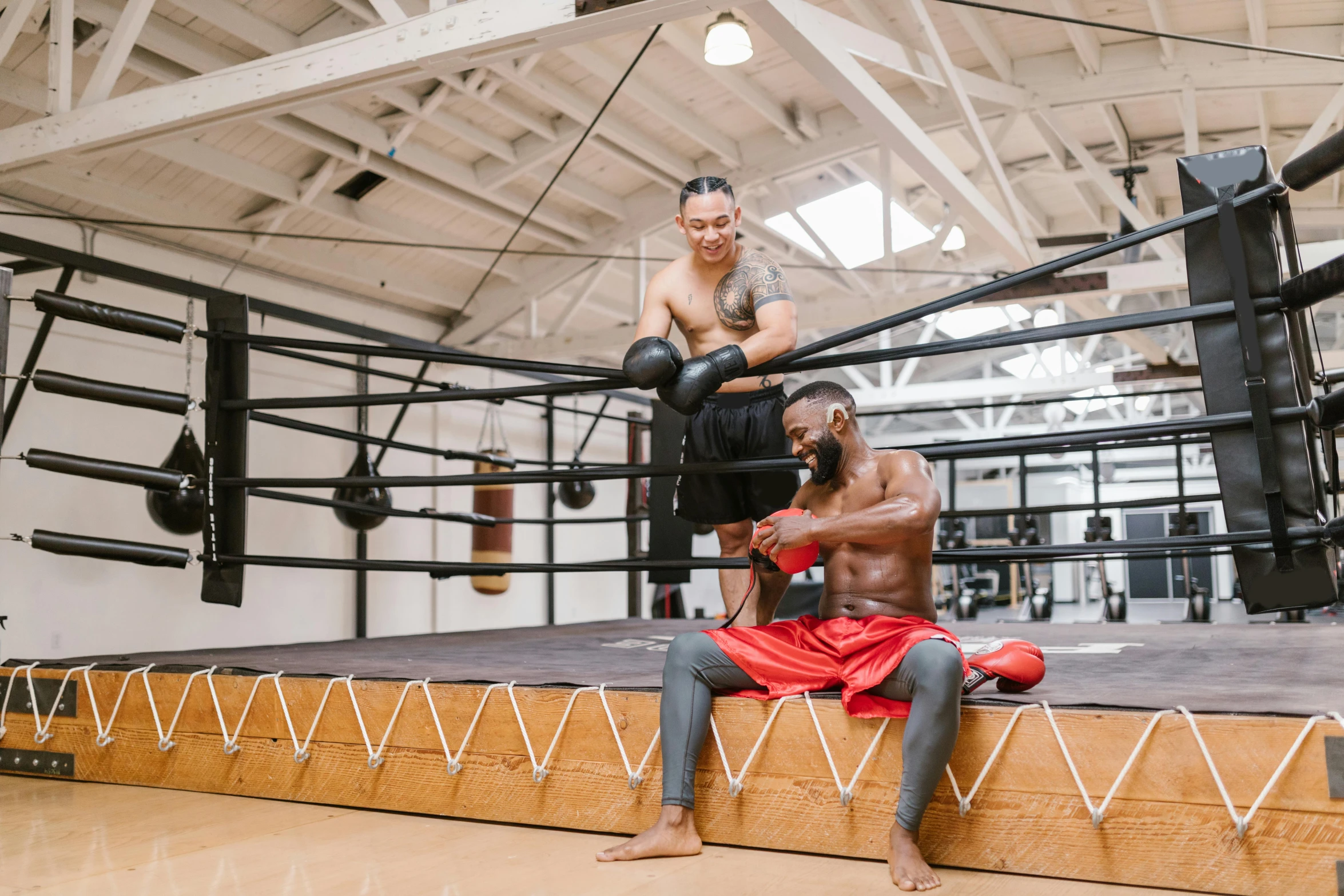 two men sitting on the edge of a boxing ring