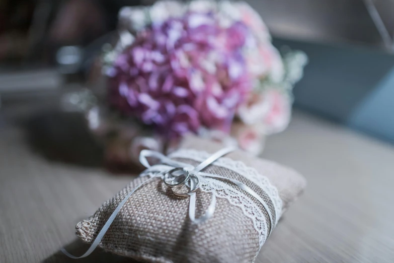 a small bag with white string sits next to a flower bouquet