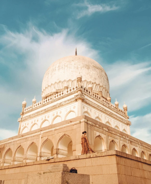 the dome and base of a white mosque with a blue sky in the background