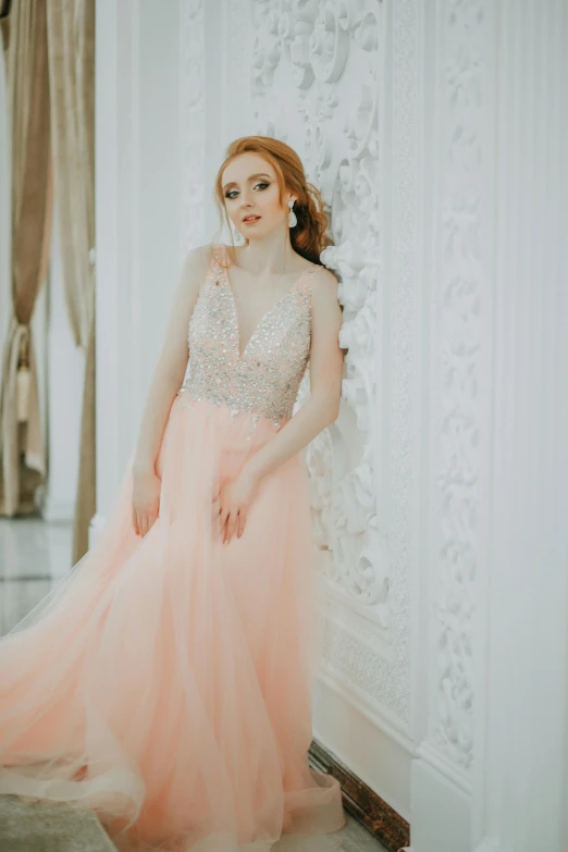 a young woman standing against a wall in an elegant gown