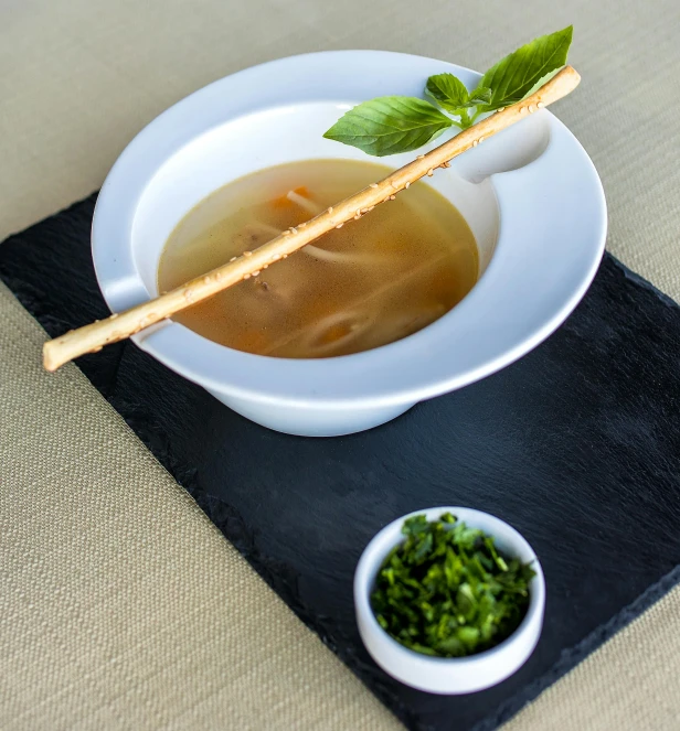 soup served on black place mat with silver spoon and small bowl