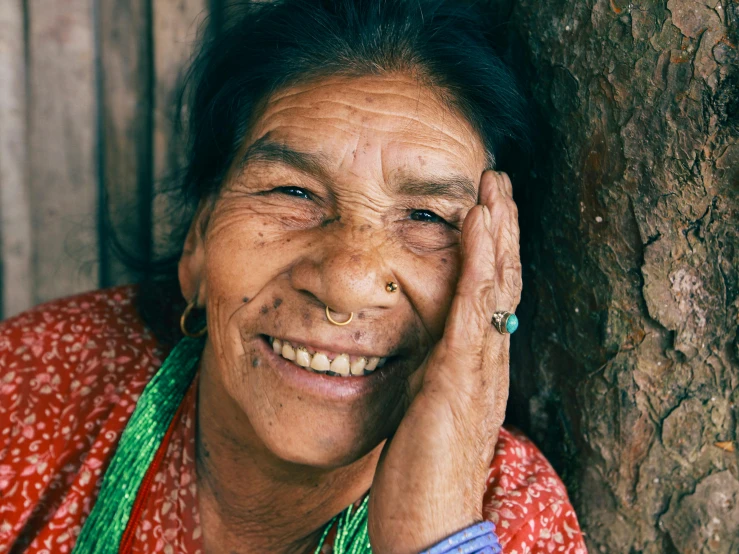 an old woman smiling with a tree in front of her