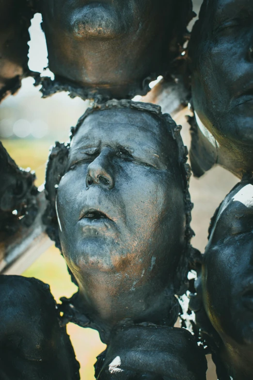 the face and upper half of a sculpture made with black clay