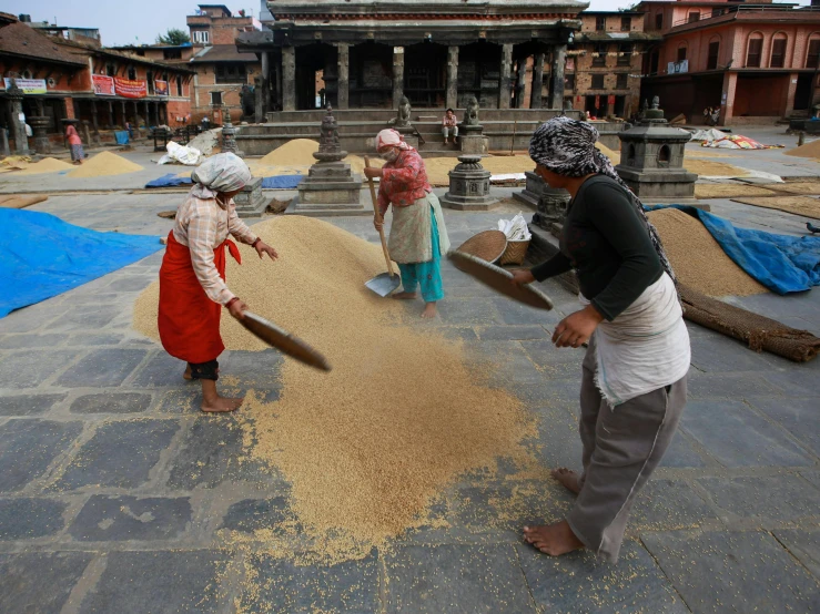 several people standing on the sidewalk by an ancient city