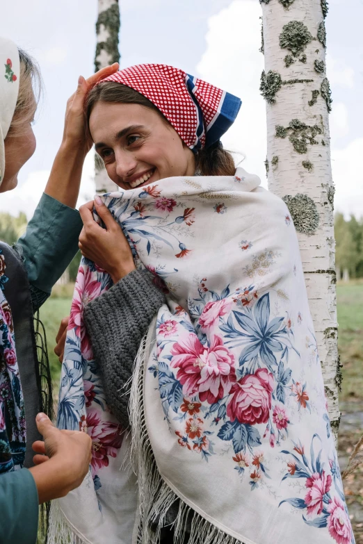 a woman adjusting a scarf on another lady's head