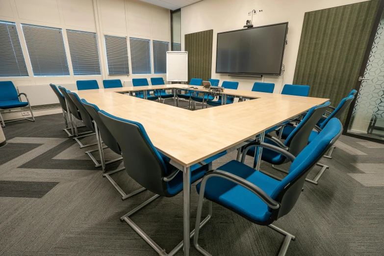 a conference table with chairs and a projector screen on one wall